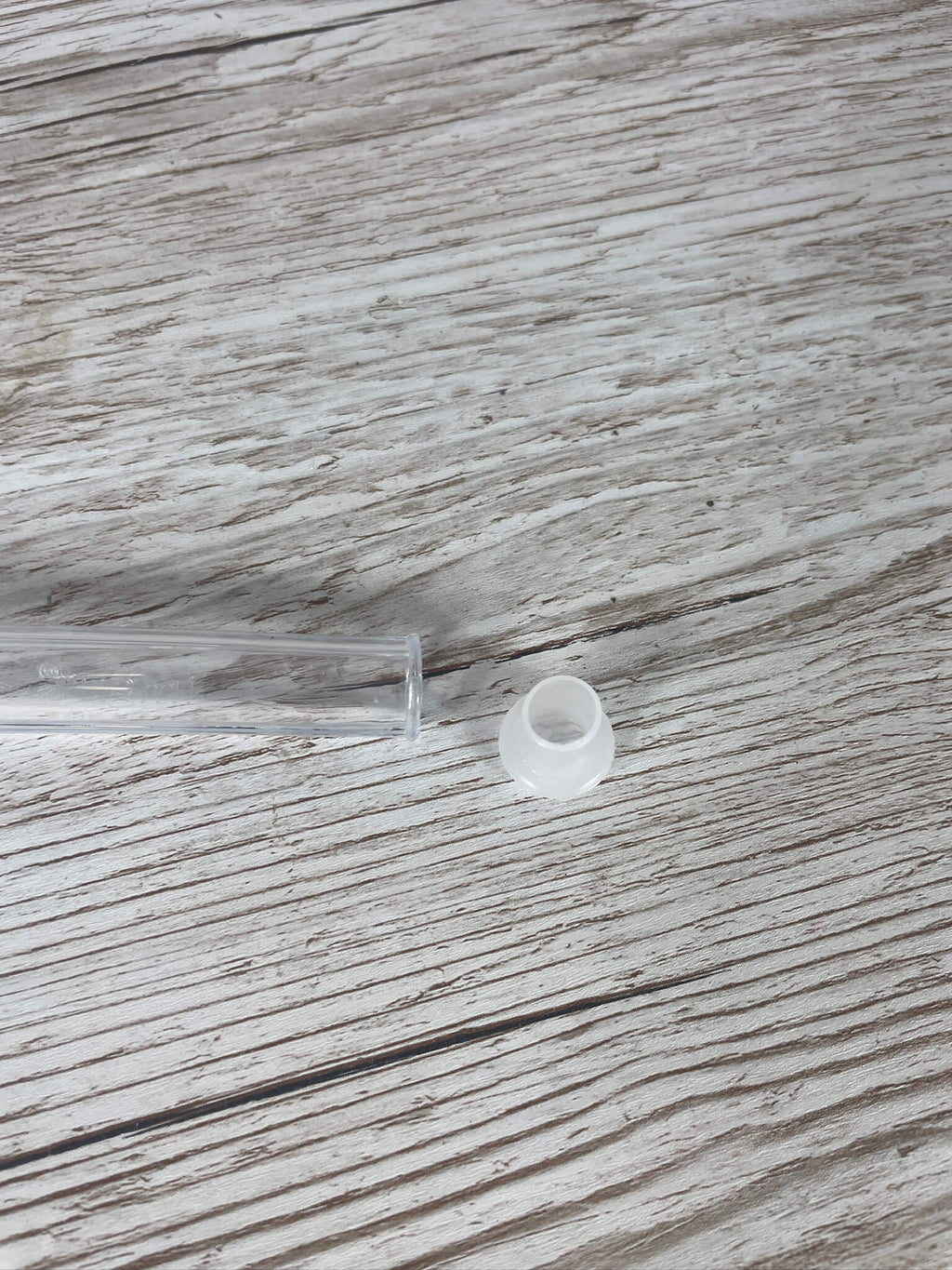 Das abnehmbare, weiße Kunststoff-Reduzierhütchen neben dem schmalen Auslass des Königinnen-Abfangglases.