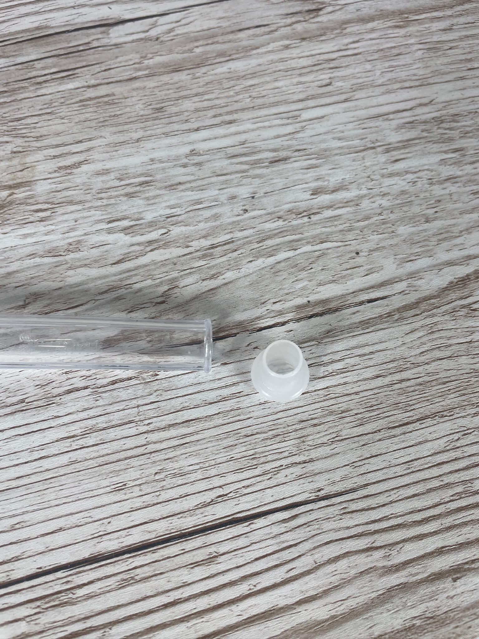 Das abnehmbare, weiße Kunststoff-Reduzierhütchen neben dem schmalen Auslass des Königinnen-Abfangglases.