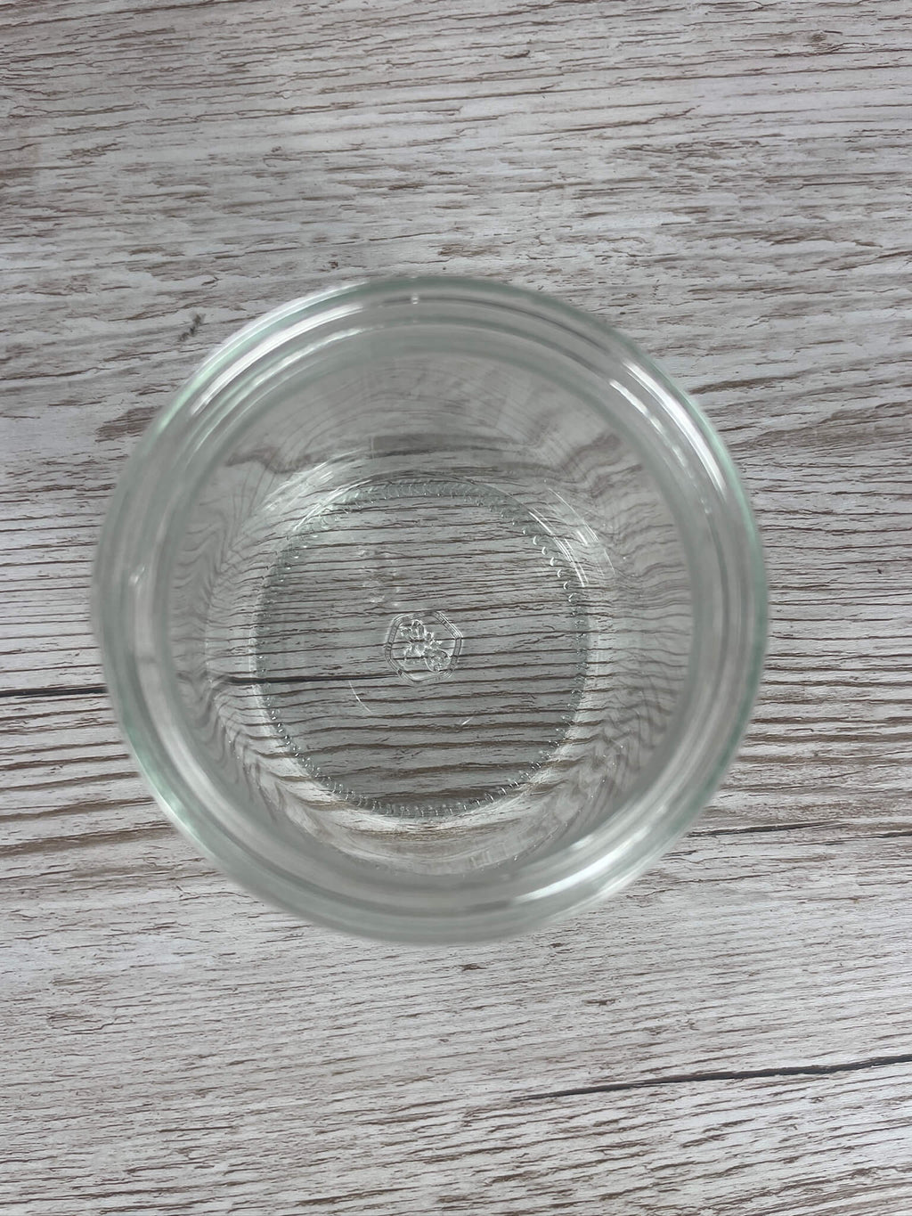 Direkte Draufsicht in ein leeres Neutralglas 500g mit Sicht auf das geprägte Glaslogo am Flaschenboden